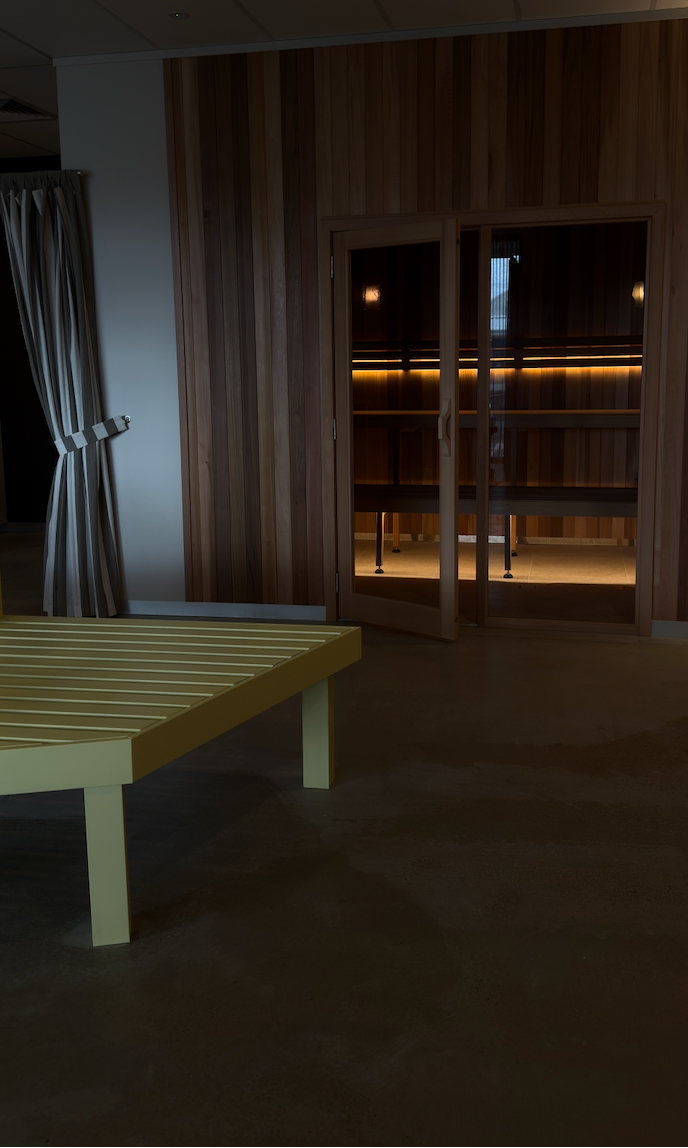 Dark room with a wooden bench and a door leading to a brighter area.